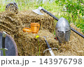 Medieval armor weapons wooden drinking vessels arranged on straw in a rustic outdoor display 143976798