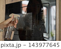 Hand spraying cleaning liquid onto microwave door in kitchen. Concept of household hygiene 143977645