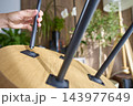 Close up of person attaching black metal leg to wooden table using threaded screw connection 143977649