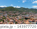 Aerial panorama hillside town beneath lush green mountains clear summer day 143977720