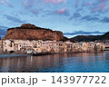 Sicilian seaside town dusk beneath dramatic rocky headland and pastel evening sky 143977722