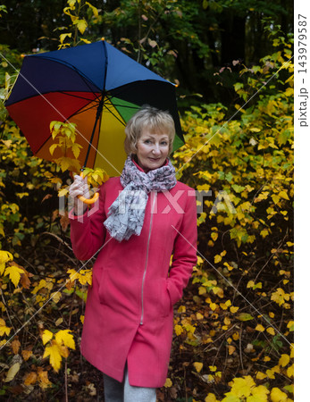 Active senior woman holding colorful umbrella smiling and enjoying autumn wellness in park. Mature female lifestyle and healthy aging Active senior woman holding colorful umbrella smiling and enjoying autumn wellness in park. Mature female lifestyle and healthy aging 143979587