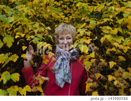 Happy senior woman in pink coat smiling outdoors in autumn park. Active elderly lifestyle, healthy aging and seasonal wellness concepts. 143980588