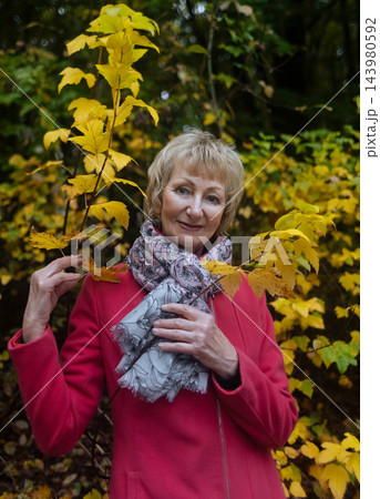 Happy senior woman in pink coat smiling outdoors in autumn park. Active elderly lifestyle, healthy aging and seasonal wellness concepts. Happy senior woman in pink coat smiling outdoors in autumn park. Active elderly lifestyle, healthy aging and seasonal wellness concepts. 143980592
