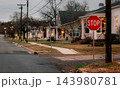 JEFFERSON, TEXAS: A red stop sign stands at a quiet street corner in a historic residential neighborhood illuminated with Christmas lights at dusk. 143980781