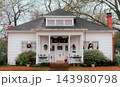 JEFFERSON, TEXAS: A historic white wooden cottage with a front porch, dormer window, and red brick chimney decorated with Christmas wreaths and festive greenery. 143980798