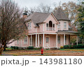 JEFFERSON, TEXAS: A stunning two-story pink Victorian home featuring a corner turret tower, wraparound front porch, and historic architectural details surrounded by fall foliage. 143981180