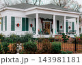 JEFFERSON, TEXAS: A classic white historic home adorned for Christmas with green shutters, red bows, wreaths, a wrought-iron fence, and holiday decorations on the front porch. 143981181