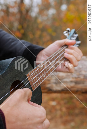 Human interaction with wooden musical instrument ukulele guitar, emphasizing leisure creativity and personal expression. Concept of peaceful environment mood of outdoor recreation and acoustic music 143981987