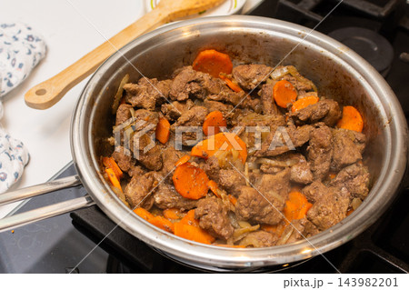 Beef liver and carrot pieces cook in a metal pan on a kitchen stove during food preparation for pate at home Beef liver and carrot pieces cook in a metal pan on a kitchen stove during food preparation for pate at home 143982201