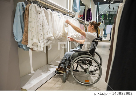 A Caucasian woman in a wheelchair shopping at a mall. A Caucasian woman in a wheelchair shopping at a mall. 143982992