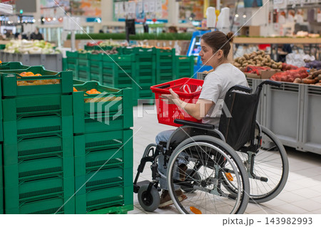 A Caucasian woman in a wheelchair buys fruit at a supermarket. 143982993