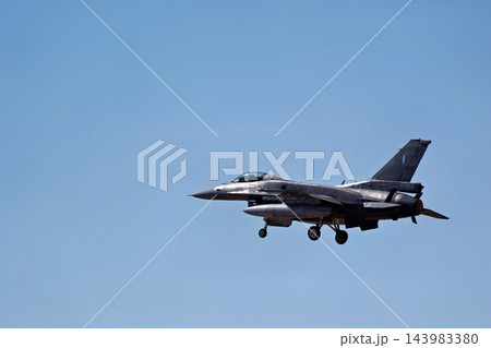 Military fighter jet flying with landing gear deployed against a clear blue sky during approach Military fighter jet flying with landing gear deployed against a clear blue sky during approach 143983380