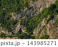Steep limestone cliff with green vegetation 143985271