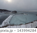 冬のウトロ港に広がる薄氷と雪に覆われた防波堤 143994284