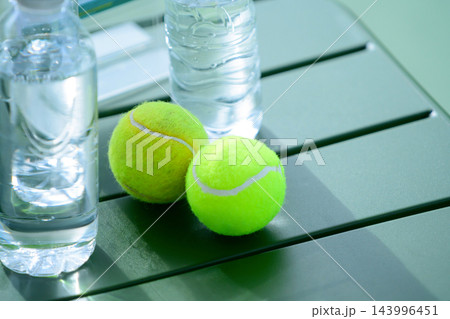 Two Tennis Balls and Water Bottles on Green Table 143996451