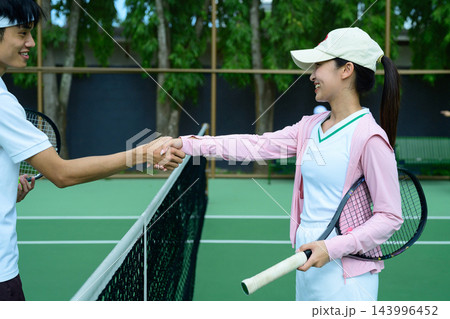 Tennis Players Shaking Hands Over Net After Match on Outdoor Court Tennis Players Shaking Hands Over Net After Match on Outdoor Court 143996452
