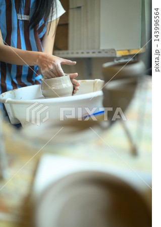Artisan Potter Shaping Ceramic Bowl on Pottery Wheel in Creative Studio Workshop 143996564