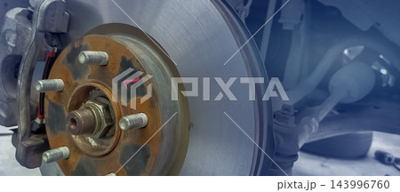 Car disc brake rotor and caliper exposed during wheel removal at an automotive garage, showing a mechanic service area for brake inspection, tire replacement, maintenance and road safety. 143996760