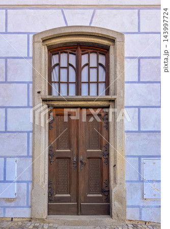 An old double wooden door set in a prominent stone archway An old double wooden door set in a prominent stone archway 143997724