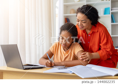 Caring black mother helping her daughter complete homework at desk at home 144002235