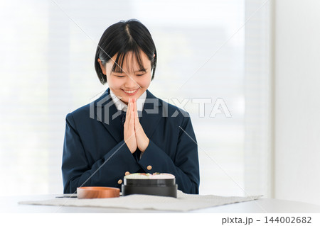 お弁当の前で手を合わせる制服姿の女子学生 お弁当の前で手を合わせる制服姿の女子学生 144002682