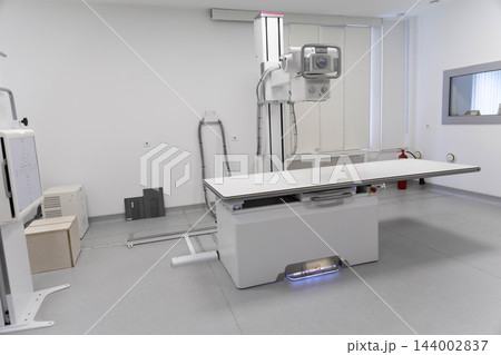 Empty modern diagnostic radiography room equipped with digital medical x-ray machine, examination table, radiological imaging column, healthcare technology setup. 144002837