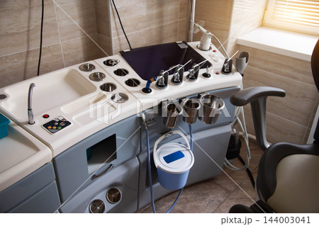 Modern medical workstation equipped with diagnostic instruments, specialized tools, metal containers, and patient examination chair in clinic interior of ENT doctor. Modern medical workstation equipped with diagnostic instruments, specialized tools, metal containers, and patient examination chair in clinic interior of ENT doctor. 144003041