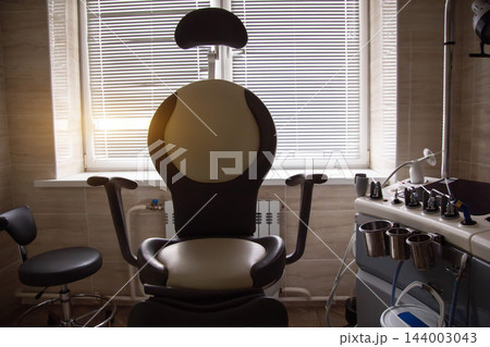 Modern otolaryngology clinic interior featuring ergonomic patient examination chair beside diagnostic workstation unit and instruments in front of window with blinds Modern otolaryngology clinic interior featuring ergonomic patient examination chair beside diagnostic workstation unit and instruments in front of window with blinds 144003043