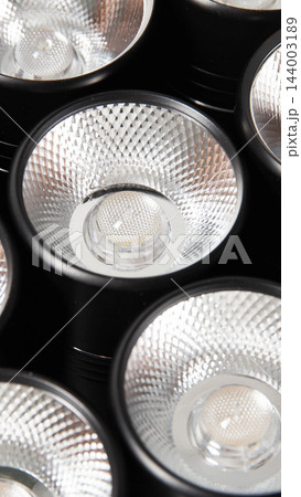 Close-up of multiple modern LED light bulbs with textured silver dimpled reflectors in a sleek black lighting fixture, showcasing advanced illumination technology vertical photo Close-up of multiple modern LED light bulbs with textured silver dimpled reflectors in a sleek black lighting fixture, showcasing advanced illumination technology vertical photo 144003189
