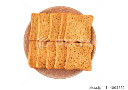 Whole grain homemade bread on a ceramic plate, isolated on a white background. Traditional bakery. Pieces of bread. Top view. Whole grain homemade bread on a ceramic plate, isolated on a white background. Traditional bakery. Pieces of bread. Top view. 144003231