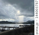雲の切れ間から差し込む光の筋と湾 木製の桟橋と山並みの風景 薄明光線 写真素材 雲の切れ間から差し込む光の筋と湾 木製の桟橋と山並みの風景 薄明光線 写真素材 144003787