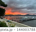 オレンジ色に染まる夕焼けの空と山のシルエット 桟橋の漁船と護岸 横位置 写真素材 オレンジ色に染まる夕焼けの空と山のシルエット 桟橋の漁船と護岸 横位置 写真素材 144003788