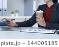Close Up of Businesswoman Hands Holding Coffee and Pointing Pen at Laptop 144005185