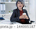Businesswoman Taking a Coffee Break and Looking Out Window in Office 144005187