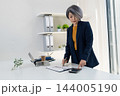 Businesswoman Standing at Desk Analyzing Financial Charts 144005190