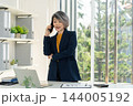 Businesswoman Standing and Talking on Smartphone in Office 144005192