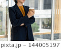 Businesswoman Enjoying Coffee Break by Office Window 144005197
