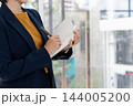 Close Up of Businesswoman Standing and Writing in Notebook at Office Desk 144005200