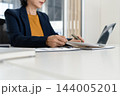 Close Up of Businesswoman Hands Reviewing Financial Documents at Desk 144005201