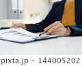 Close Up of Businesswoman Hands Reviewing Financial Documents at Desk 144005202