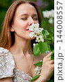 Woman in a floral dress beside white garden flowers 144008557