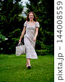 Woman with a tote bag walking through a green park 144008559
