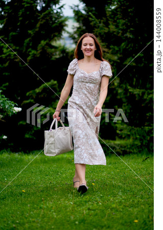 Woman with a tote bag walking through a green park 144008559
