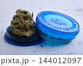 Cannabis Flower With Blue Grinder On Wooden Surface 144012097