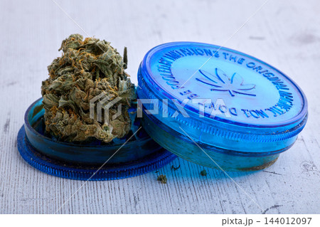 Cannabis Flower With Blue Grinder On Wooden Surface Cannabis Flower With Blue Grinder On Wooden Surface 144012097