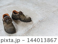 Worn work boots standing on concrete floor. 144013867