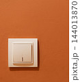 White light switch mounted on orange wall 144013870