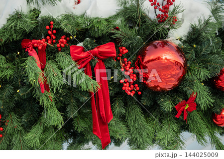 Red Christmas ball and velvet bows on snow covered fir tree Red Christmas ball and velvet bows on snow covered fir tree 144025009