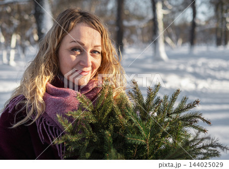 Smiling mature woman with fir branches in snowy winter park Smiling mature woman with fir branches in snowy winter park 144025029